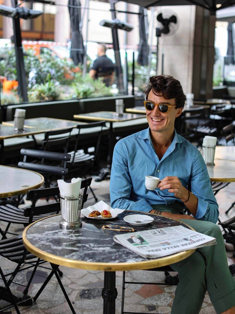 a man in a stylish blue shirt and sunglasses with a coffee