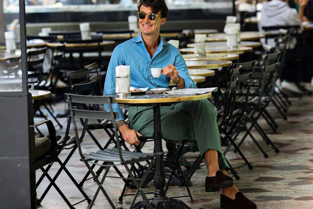 a man in a stylish blue shirt and sunglasses with a coffee