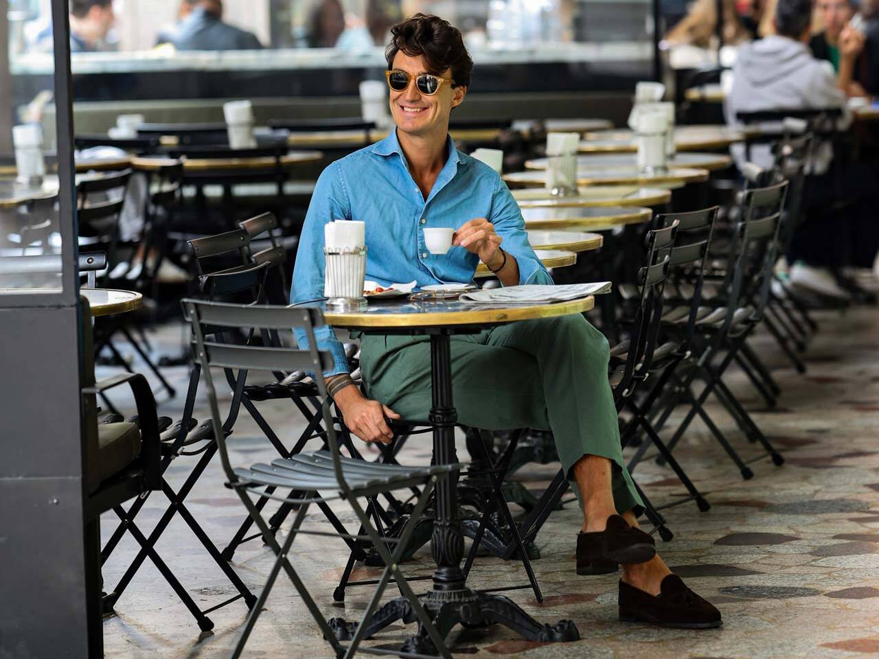 a man in a stylish blue shirt and sunglasses with a coffee