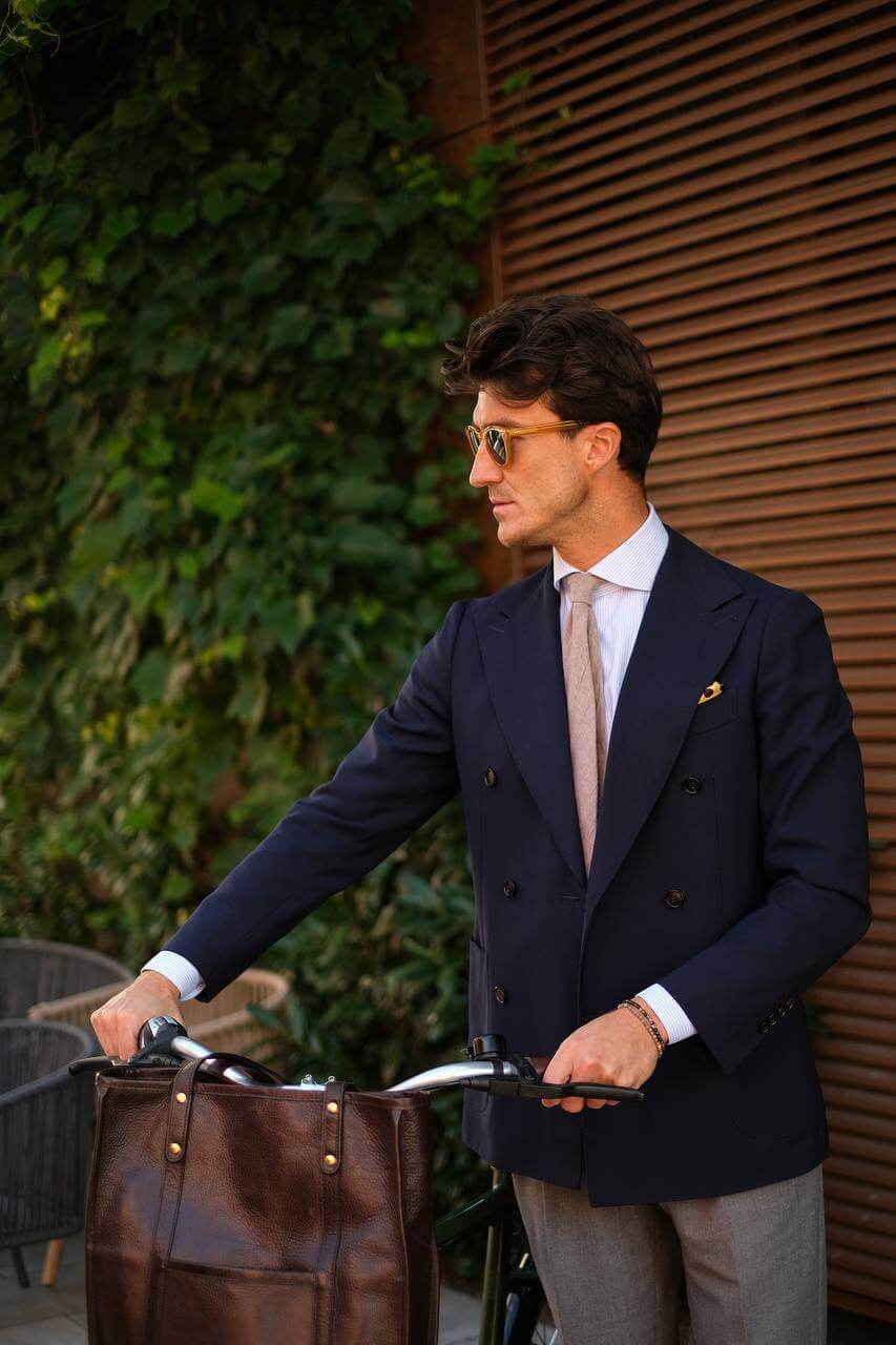 A man in a jacket with a nice shirt holds the handles of a bicycle