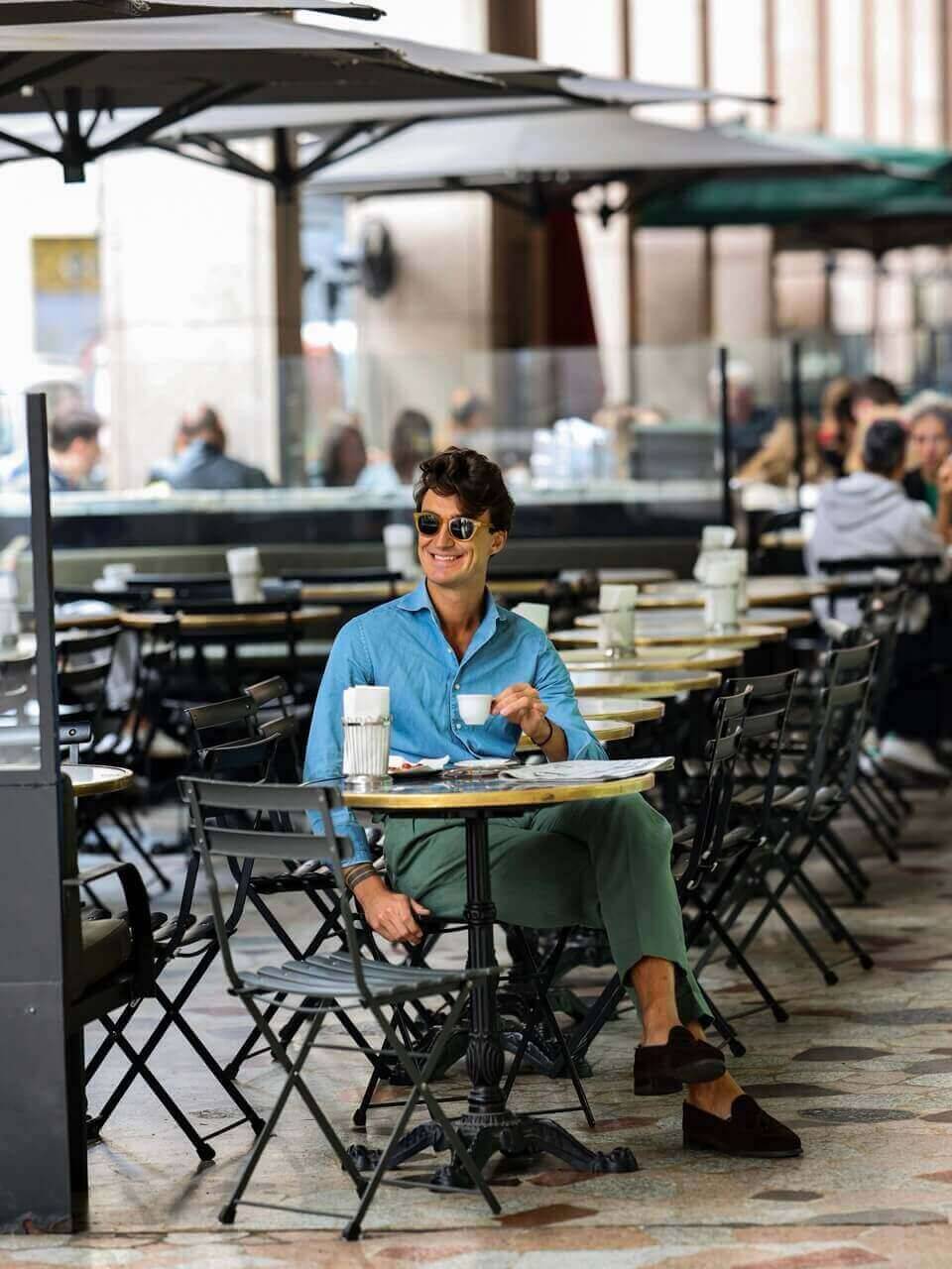 a man with a cup of espresso in a blue shirt and sunglasses