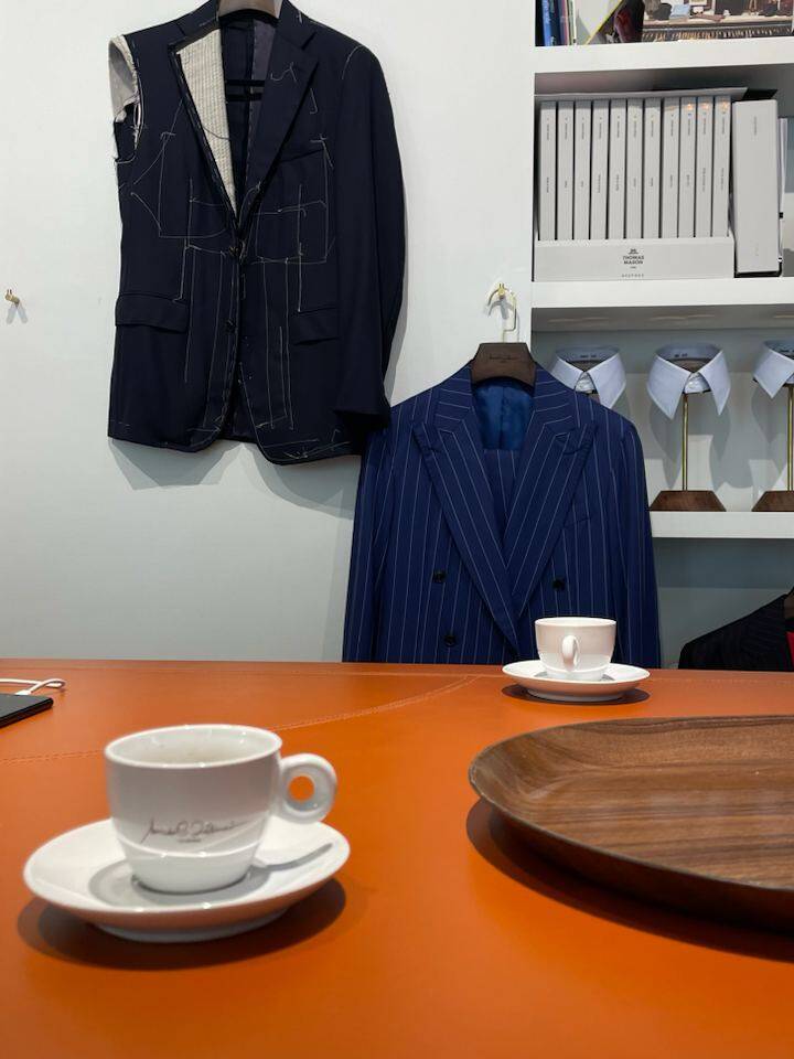 Suits and fabrics displayed in a Milan boutique during an in-person personal styling session, highlighting bespoke tailoring for a gentleman's wardrobe