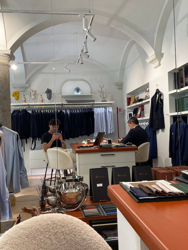 Personal stylist in a Milan boutique preparing outfits for in-person styling session with a focus on a gentleman's wardrobe