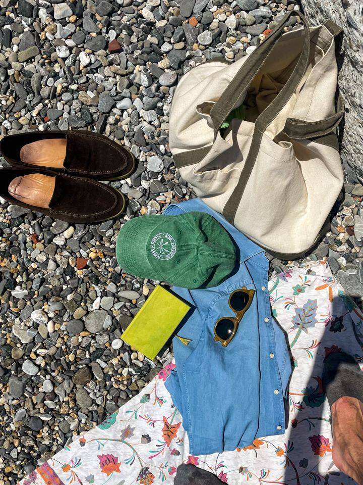 Traveler relaxing on rocky beach with historic yellow villa in the background, enjoying the sunny weather in Liguria, Italy