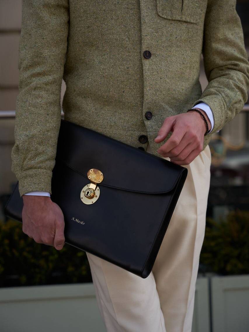 Close-up of a Anton holding a sleek black leather briefcase, emphasizing luxury and craftsmanship in fashion accessories