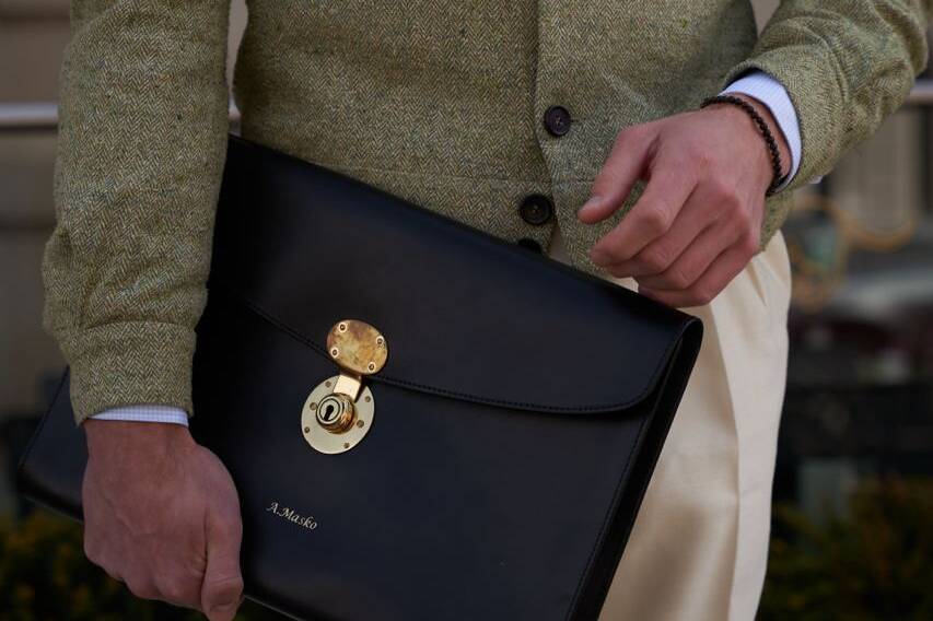 Close-up of a Anton holding a sleek black leather briefcase, emphasizing luxury and craftsmanship in fashion accessories