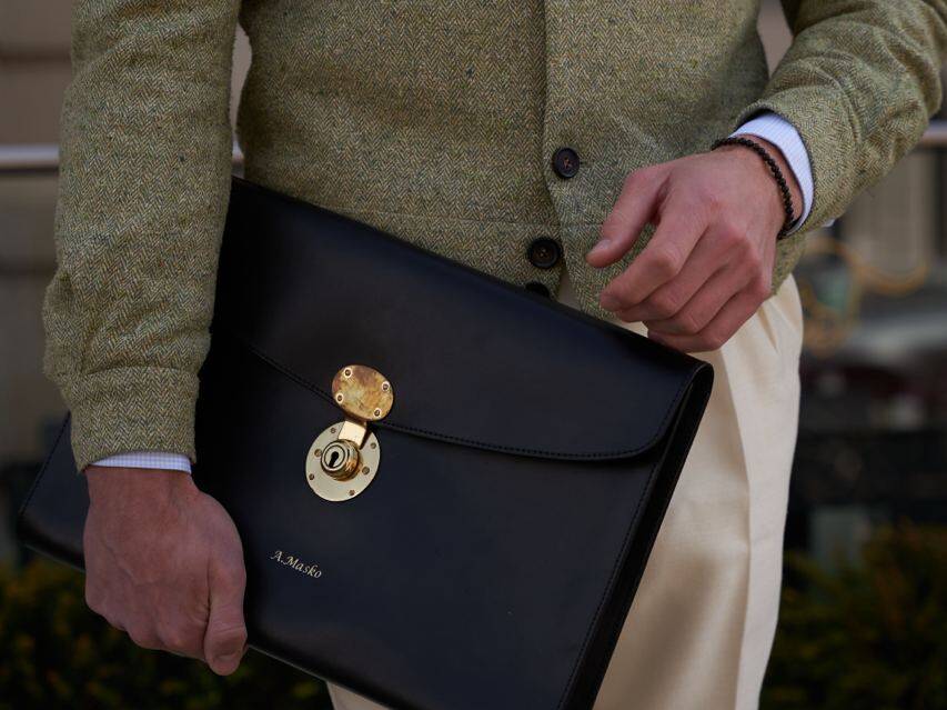 Close-up of a Anton holding a sleek black leather briefcase, emphasizing luxury and craftsmanship in fashion accessories