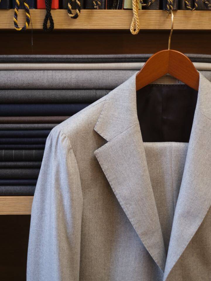 Completed suit jacket crafted with the glued method of suit construction, displayed in a tailoring shop