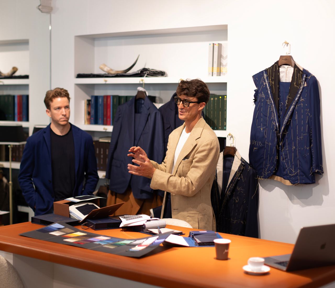 Master tailor presenting fabric choices and suit styles during a workshop in Milan, highlighting Italian tailoring craftsmanship and men's fashion