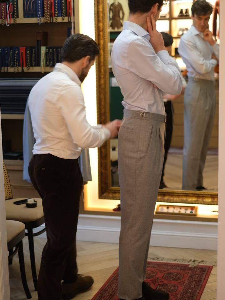 Tailor adjusting a suit during the fitting process, illustrating the glued method of suit construction for a perfect fit