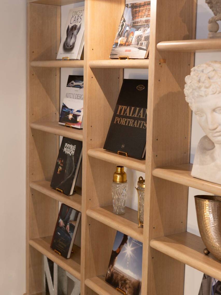 Wooden bookshelf displaying luxury design books and decor items in a workshop in Milan, reflecting an environment of creativity and sophistication during a style master class event